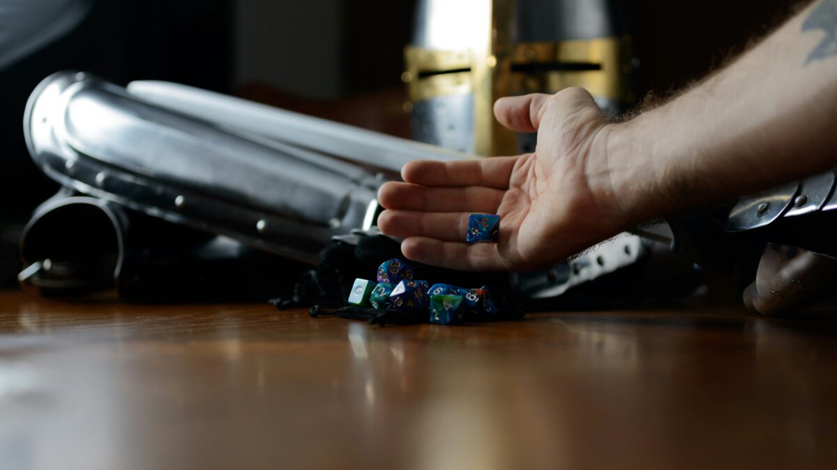 Suit of armor and dice sitting on a felt bag with a hand holding dice