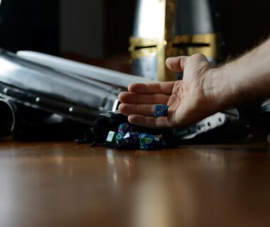 Suit of armor and dice sitting on a felt bag with a hand holding dice