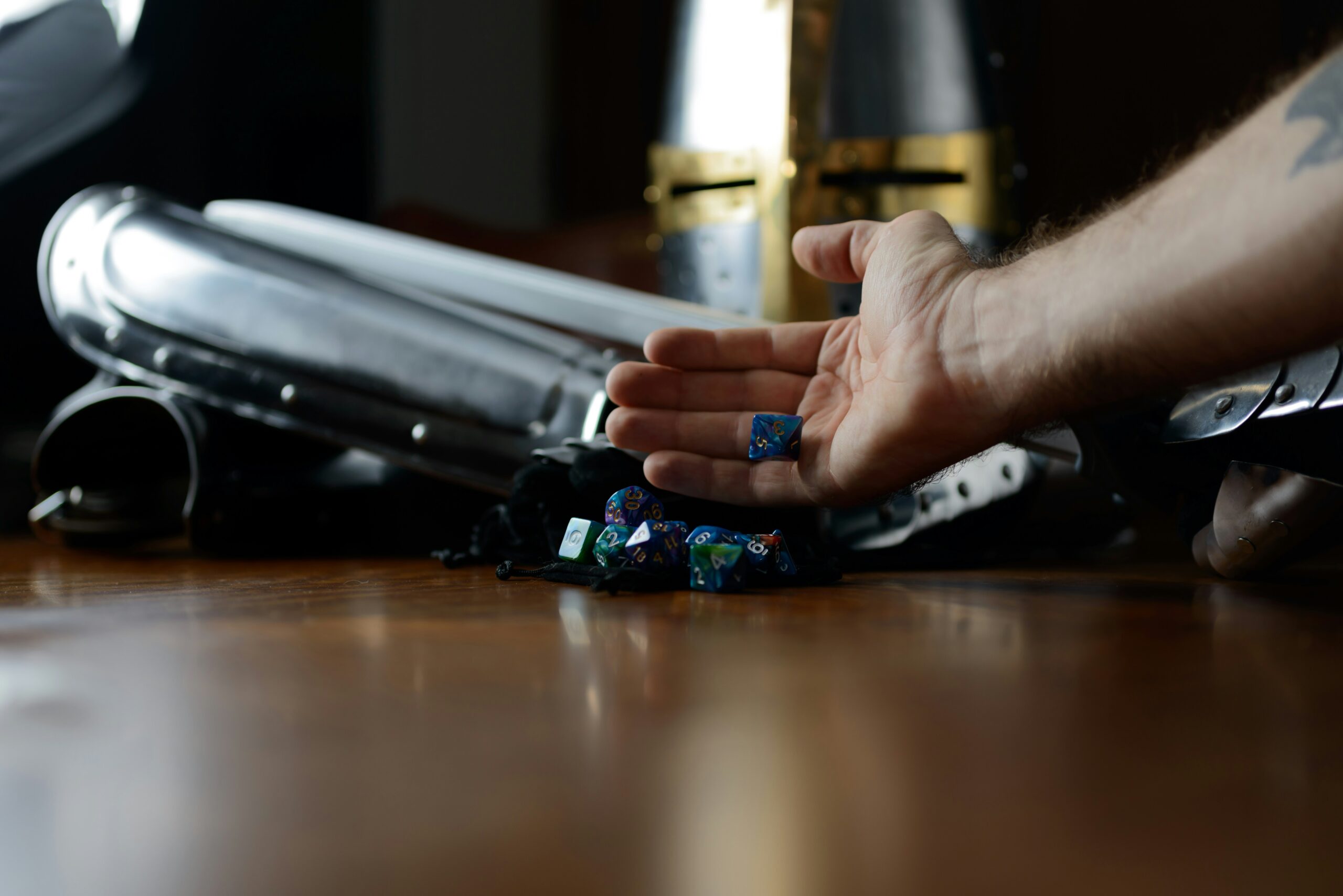 Suit of armor and dice sitting on a felt bag with a hand holding dice