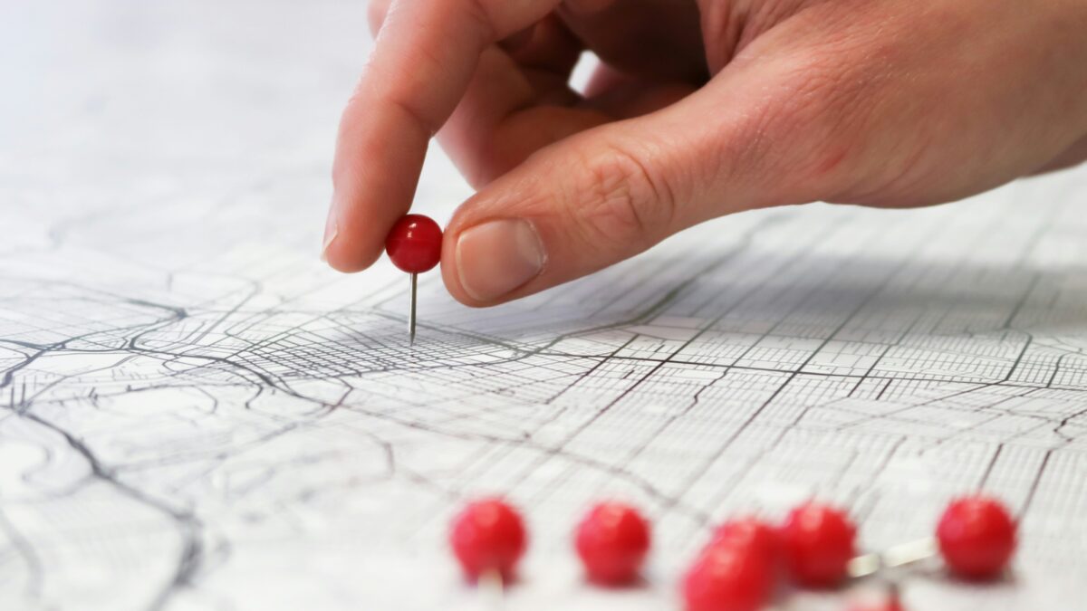 Hand putting pin in a map.